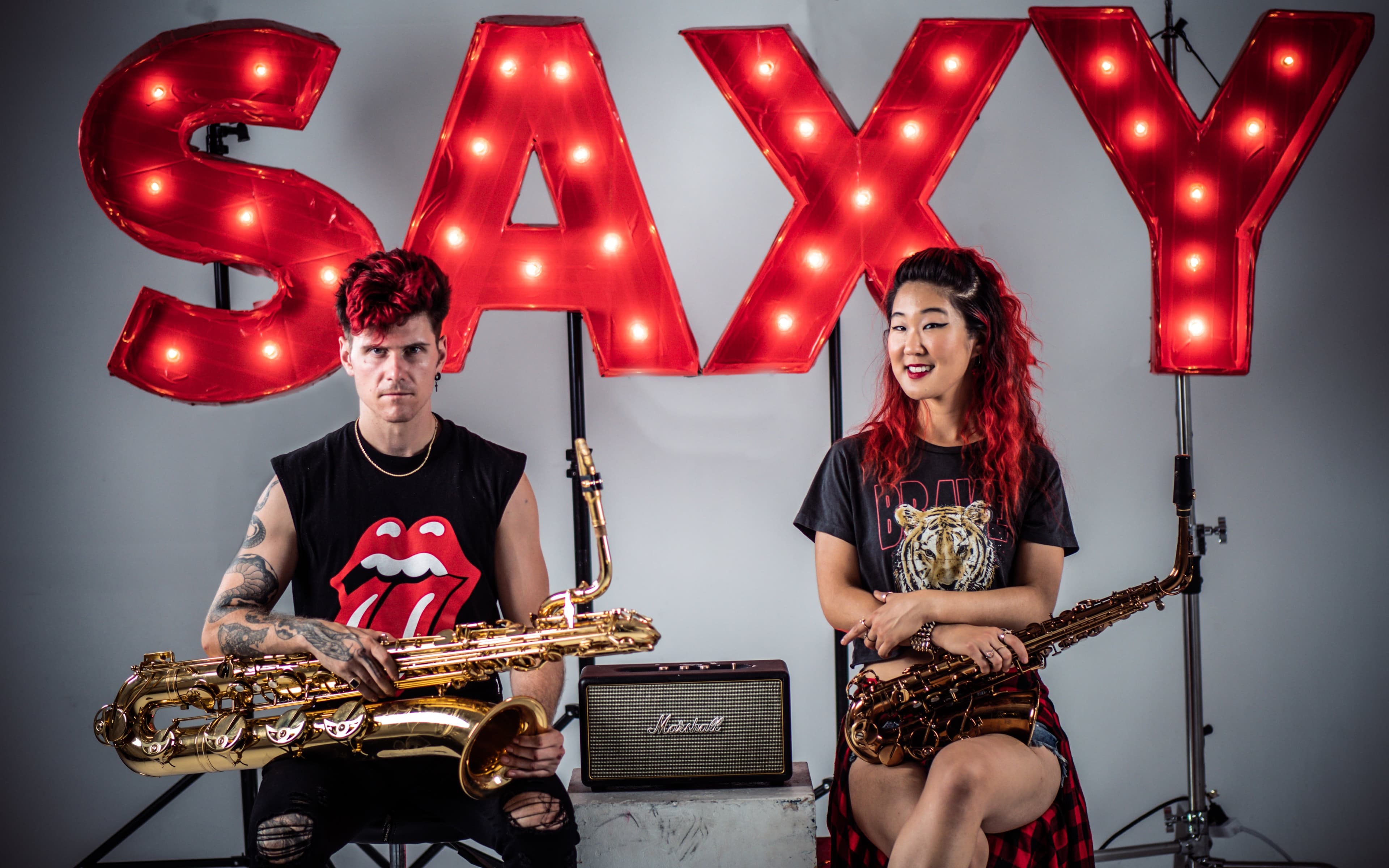 2SAXY with saxophones in front of a red SAXY marquee